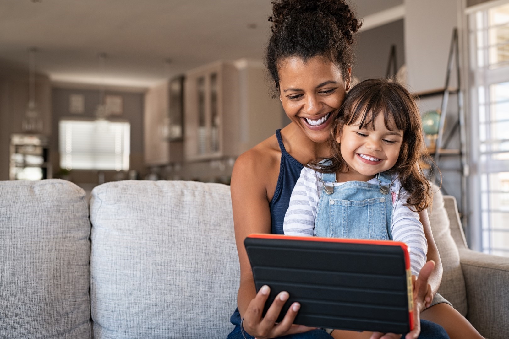 African-American smiling mother and happy daughter using digital tablet